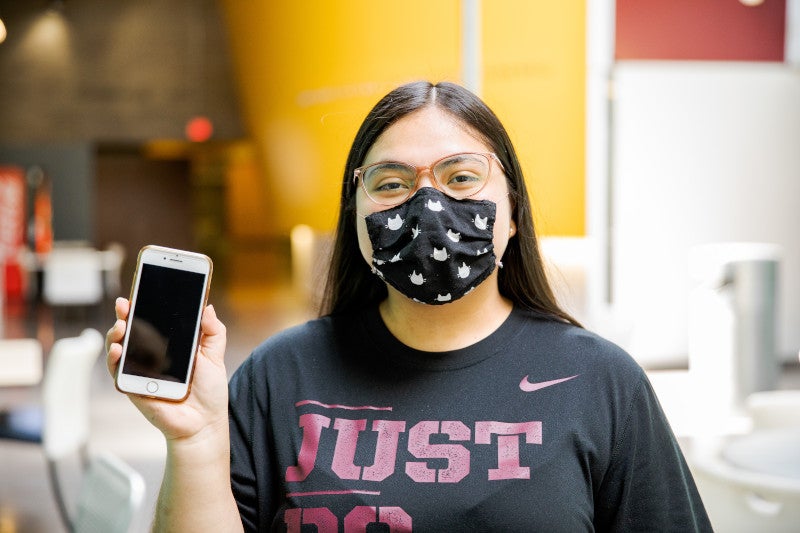 Girl holding a phone with her mask on