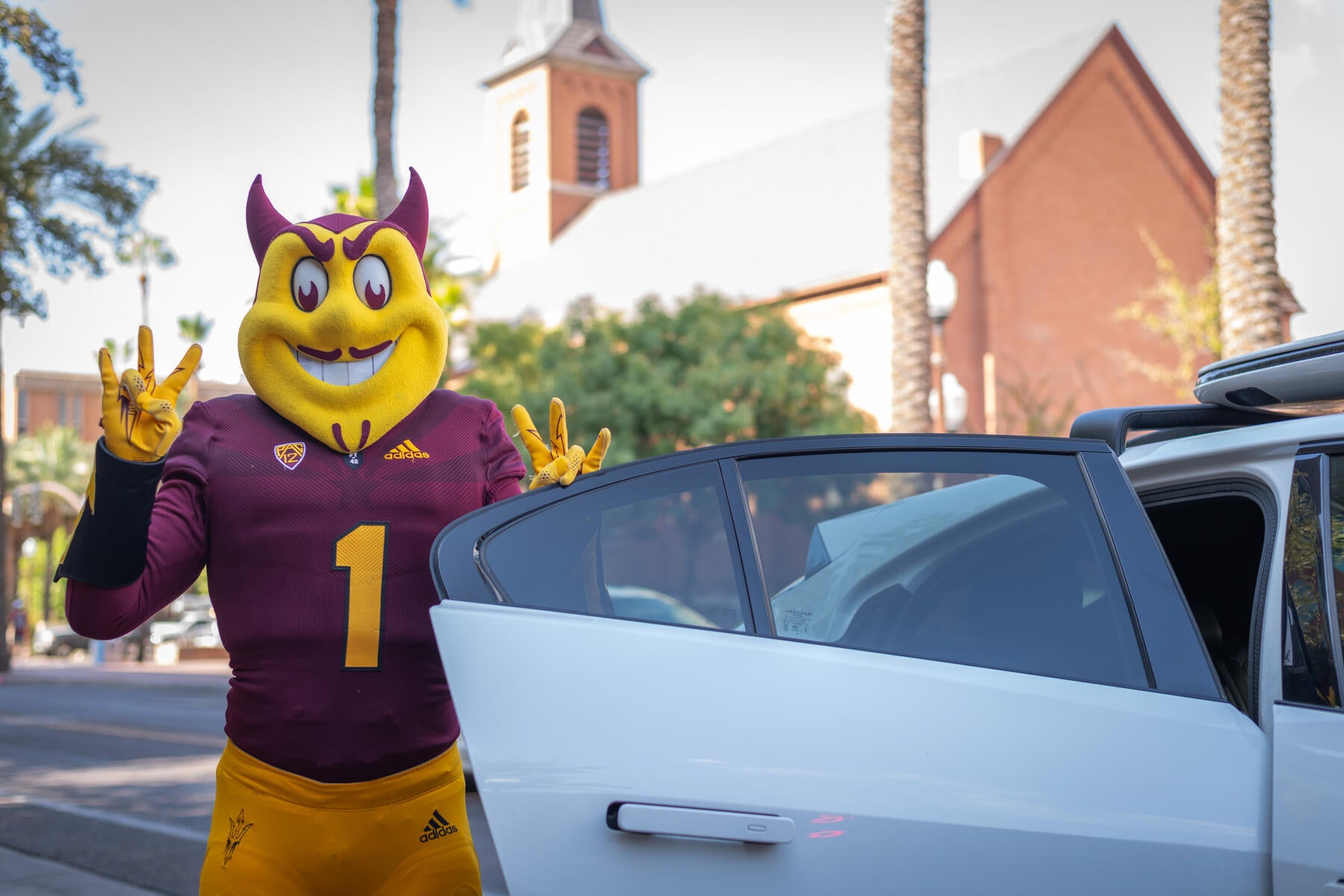 Soarky mascot standing with car door open